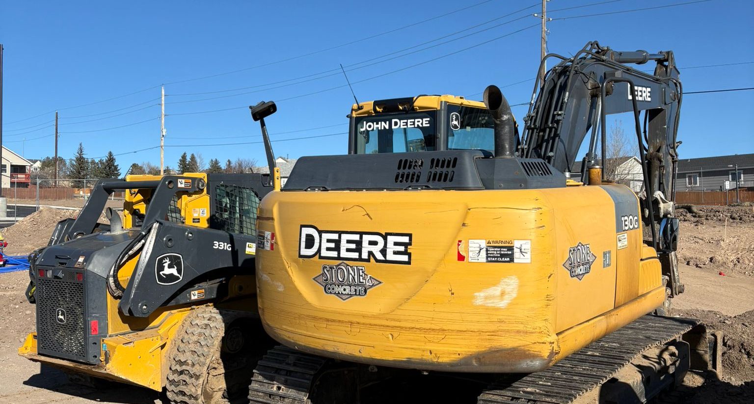 Stone & Concrete excavator and skid steer on a job site