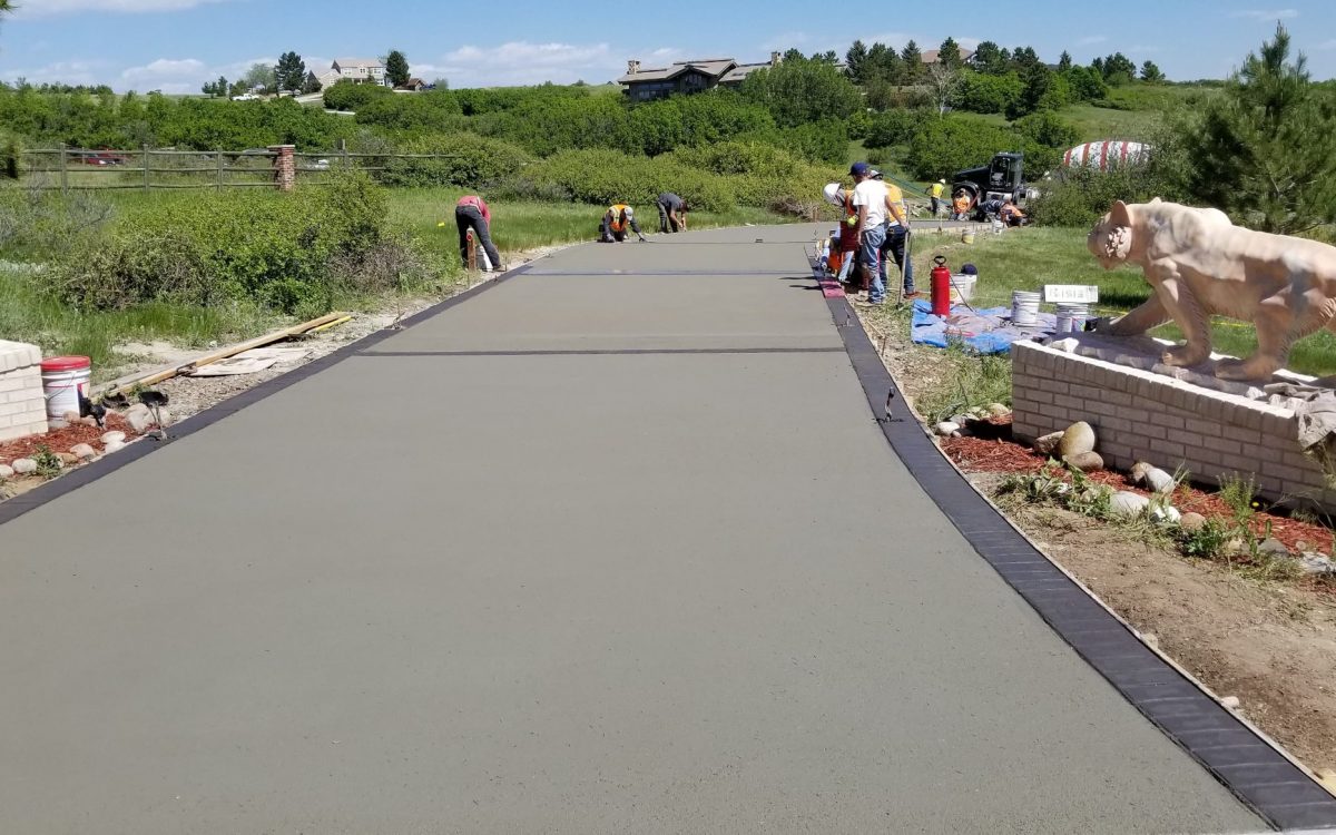 Stone & Concrete crew finishing a new concrete driveway with a stamped border