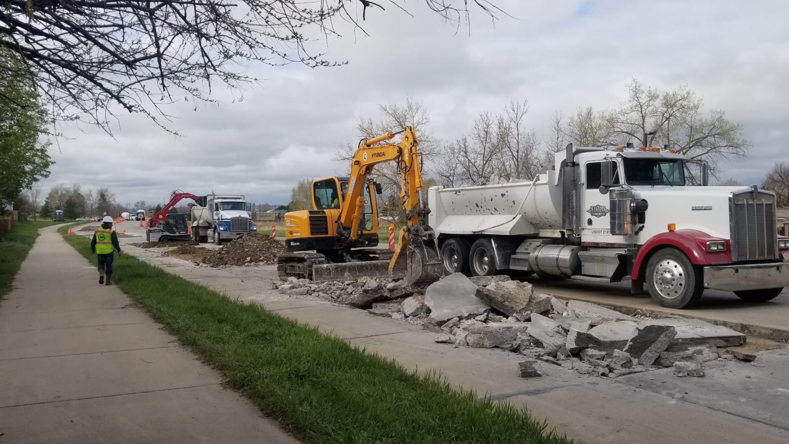 Stone & Concrete crew loading two dump trucks during concrete demo and haul-off